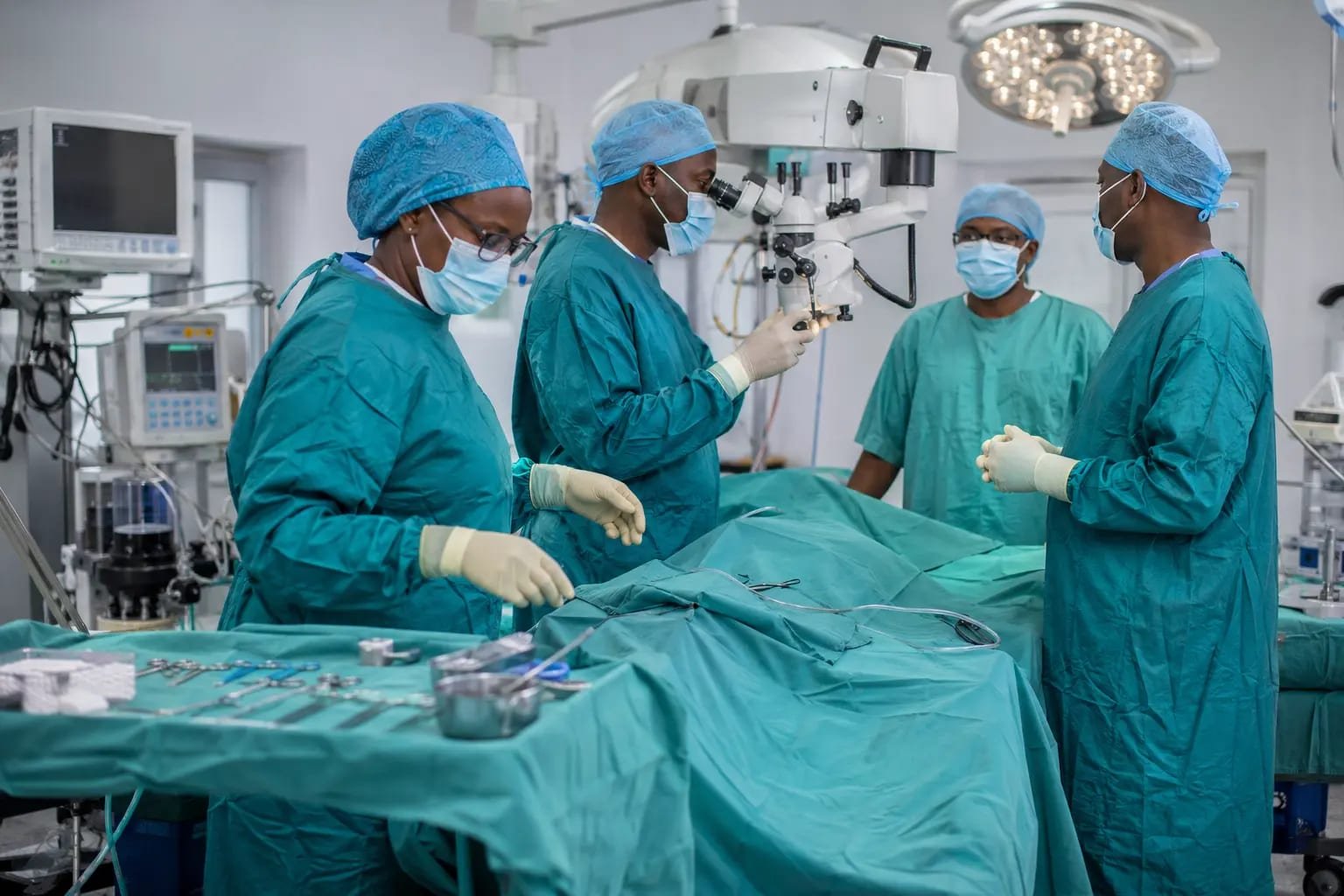 Neurosurgical team operating with a surgical microscope in a hospital theatre